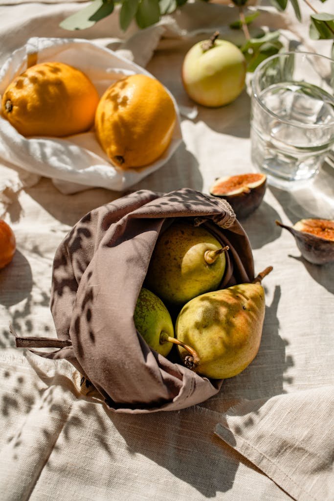 Bags with Fresh Fruits and a Glass of Water Standing in Sunlight