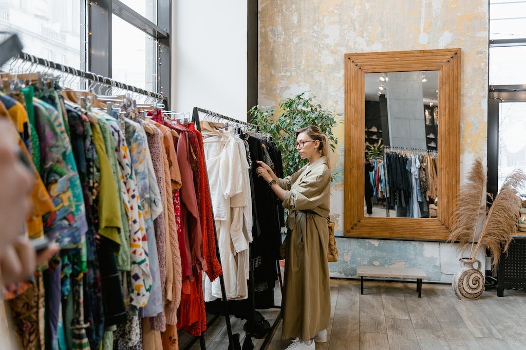 Woman in Brown Trench Trench Coat Standing Near Clothes Rack
